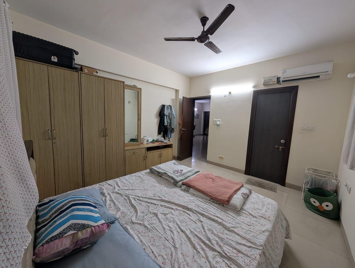Existing bedroom with a wardrobe and dressing unit on the left, the bedroom entrance ahead, and the bathroom door on the right