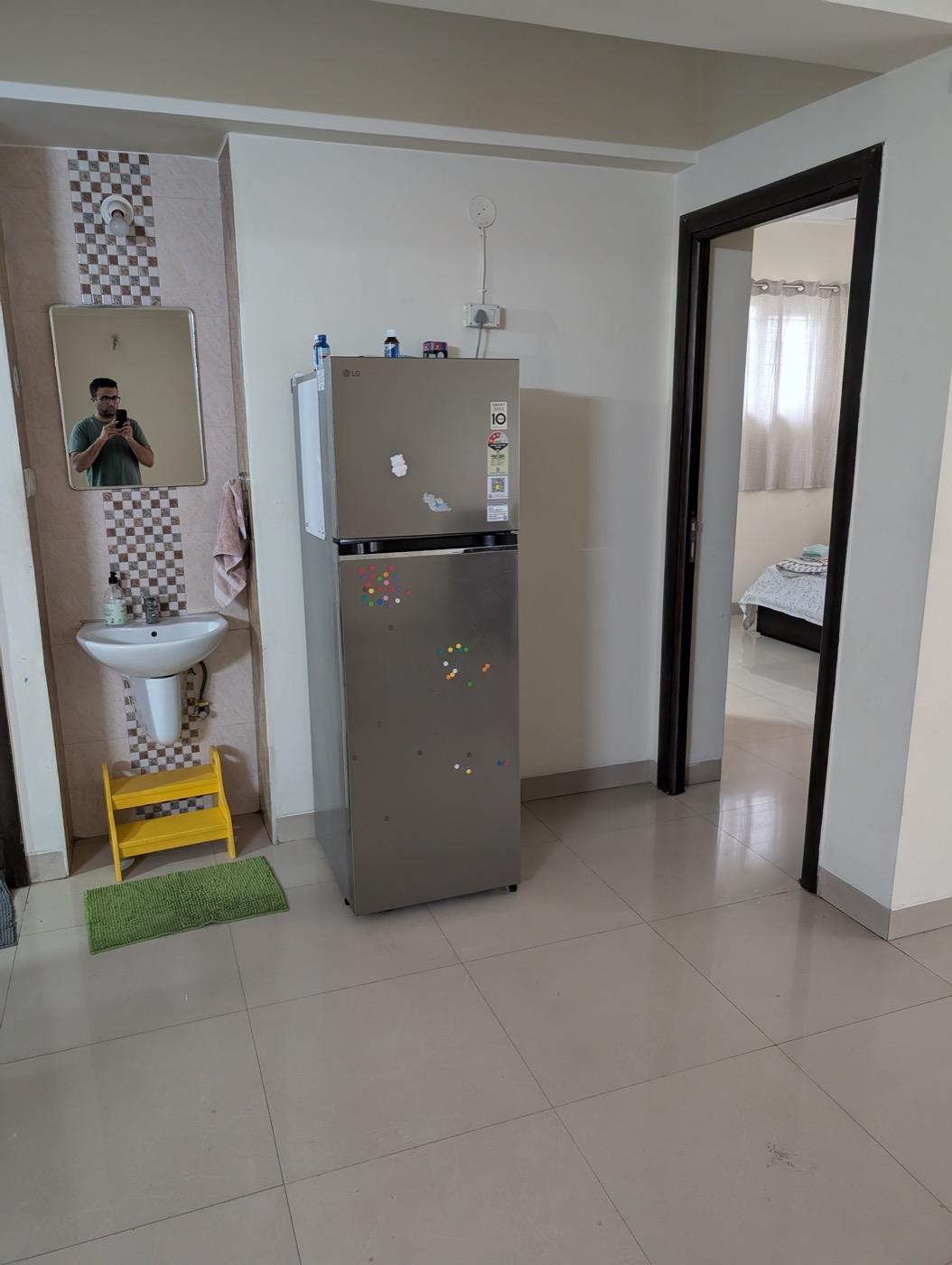 Existing basin and refrigerator beside the bedroom entrance, framed below the mirror